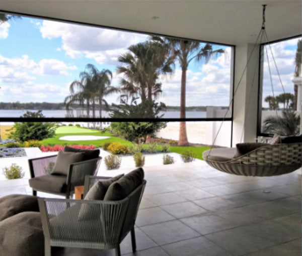Retractable motorized screens enclosing a covered outdoor living space.